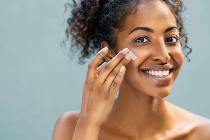 young woman applying skincare product to her face
